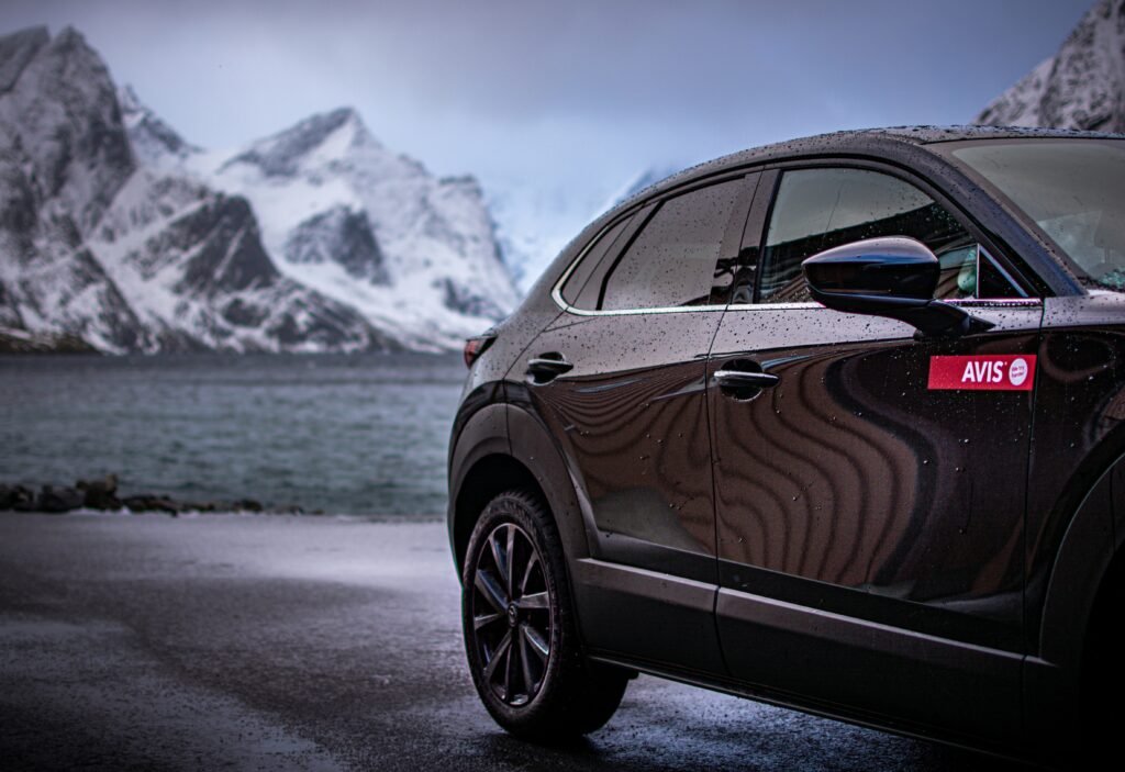 a car parked on a road by water and mountains